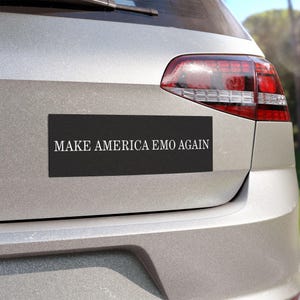 May include: A silver car with a black bumper sticker that reads "MAKE AMERICA EMO AGAIN".