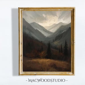 Pode incluir: Pintura a óleo de uma paisagem de montanha emoldurada em ouro. A obra retrata um vale com camadas de montanhas em tons de cinza e castanho. O céu está nublado com um vislumbre de sol. O texto "- MACWOODSTUDIO -" está na parte inferior.