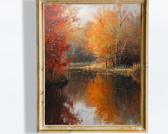 Op de afbeelding: Een ingelijst landschapsschilderij dat een serene herfstscène uitbeeldt. Het kunstwerk toont een reflecterend water omgeven door bomen met levendige rode, oranje en gele bladeren. De lijst is goudkleurig en de tekst "- MACWOODSTUDIO -" staat onderaan.