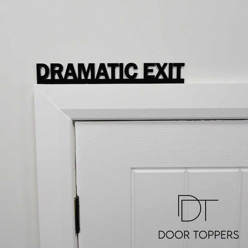 DRAMATIC EXIT Door Topper displayed above a white door frame in black recycled acrylic, ideal as a funny leaving gift or theatre gift.
