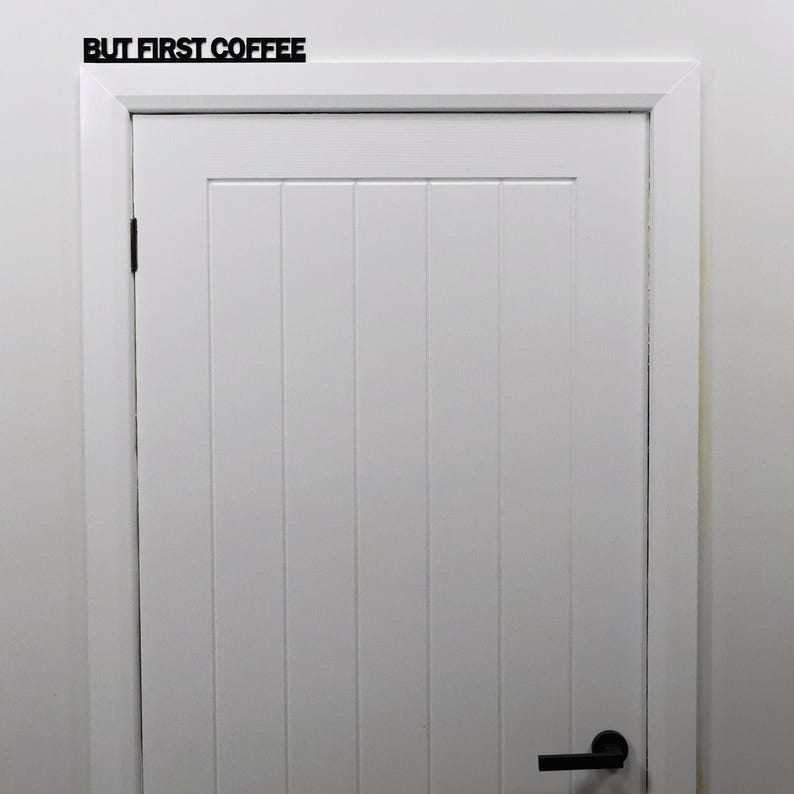 Black acrylic BUT FIRST COFFEE sign installed above a kitchen doorway.