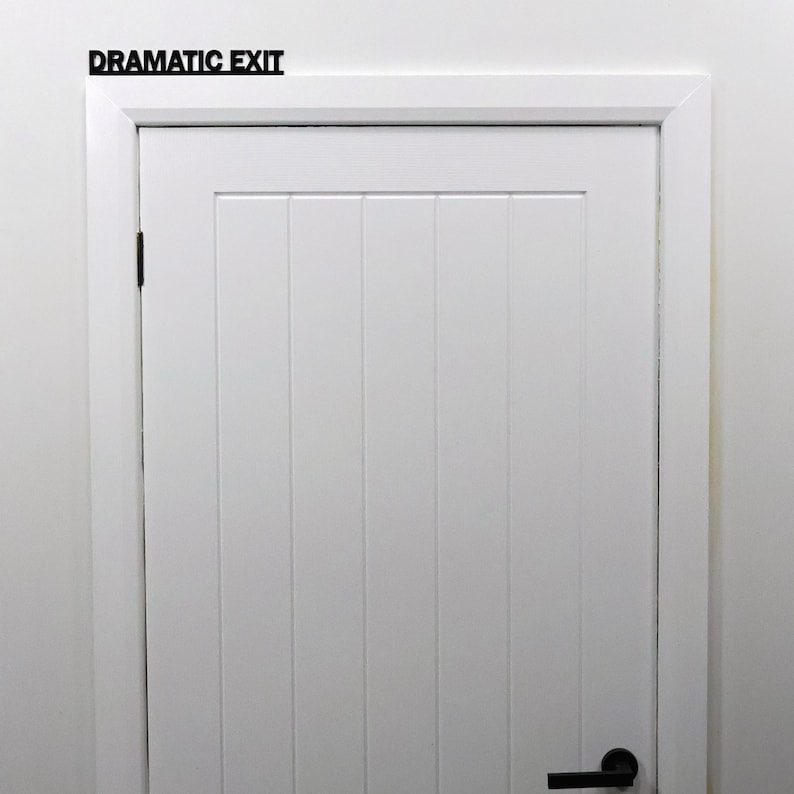 Black acrylic over door sign mounted above an interior doorway.