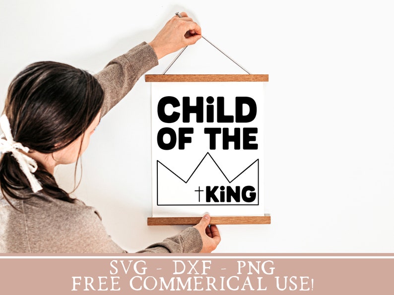 May include: A white printable sign with black text that reads "Child of the King" with a crown graphic. The sign is hanging on a white wall.
