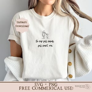 K&ouml;nnte beinhalten: Wei&szlig;es T-Shirt mit einer schwarzen Strichzeichnung einer Mutter und eines Kindes, die gehen, und dem Text "In my full hands, full heart, era."