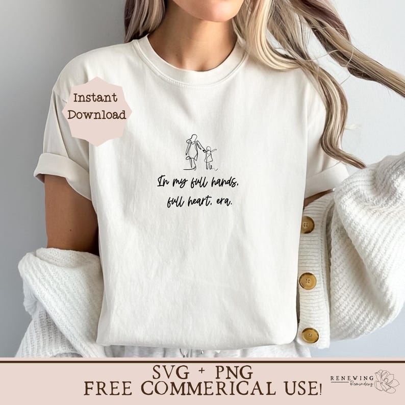 K&ouml;nnte beinhalten: Wei&szlig;es T-Shirt mit einer schwarzen Strichzeichnung einer Mutter und eines Kindes, die gehen, und dem Text "In my full hands, full heart, era."