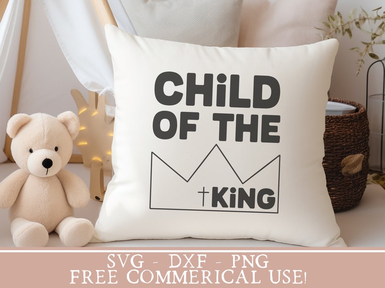 May include: White pillow with black text that reads "Child of the King" with a crown graphic.  The text is in a bold, blocky font.  The pillow is on a white surface.