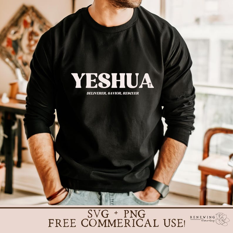 May include: A black long-sleeved shirt with the word "YESHUA" printed in white on the front. The text is followed by a small white cross and the words "DELIVERER, SAVIOR, RESCUER" in smaller white text. The shirt is being worn by a person with their hands in their pockets.