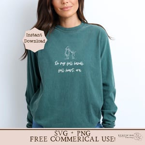 K&ouml;nnte beinhalten: Ein tealfarbenes Langarmshirt mit einer wei&szlig;en Umrandung einer Mutter und eines Kindes, die sich an den H&auml;nden halten, und dem Text "In my full hands. full heart, era." Das Shirt ist als digitaler Download in den Formaten SVG und PNG f&uuml;r kommerzielle Nutzung erh&auml;ltlich.
