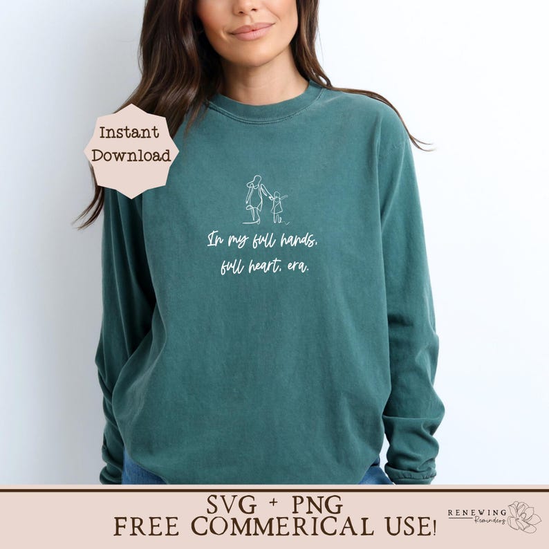 K&ouml;nnte beinhalten: Ein tealfarbenes Langarmshirt mit einer wei&szlig;en Umrandung einer Mutter und eines Kindes, die sich an den H&auml;nden halten, und dem Text "In my full hands. full heart, era." Das Shirt ist als digitaler Download in den Formaten SVG und PNG f&uuml;r kommerzielle Nutzung erh&auml;ltlich.