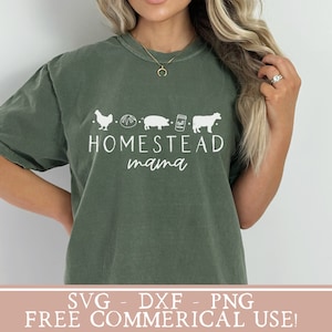 Op de afbeelding: Een groen T-shirt met een wit ontwerp met een kip, brood, varken, pot en koe met de tekst "Homestead mama".
