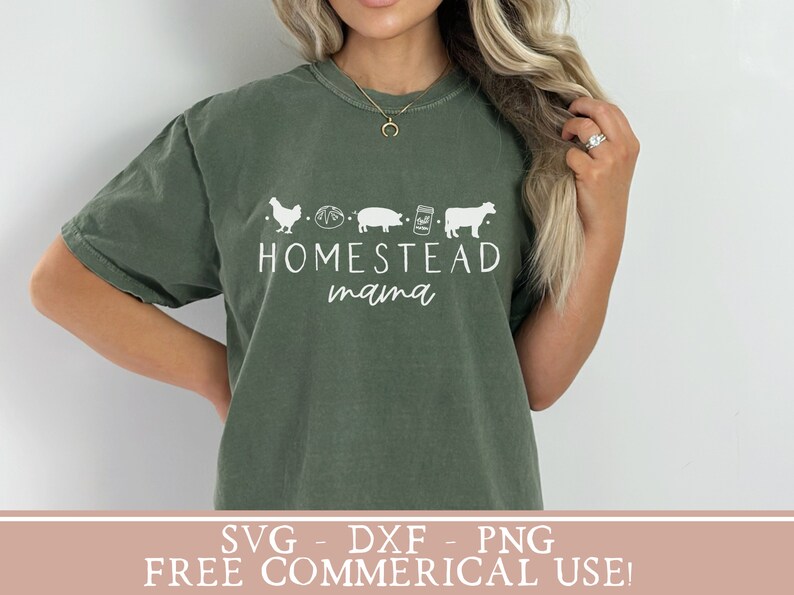 Op de afbeelding: Een groen T-shirt met een wit ontwerp met een kip, brood, varken, pot en koe met de tekst "Homestead mama".