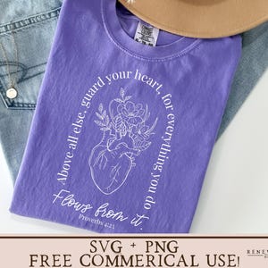May include: Purple t-shirt with a white graphic design of a heart with flowers and the text "Above all else, guard your heart, for everything you do flows from it. Proverbs 4:23"