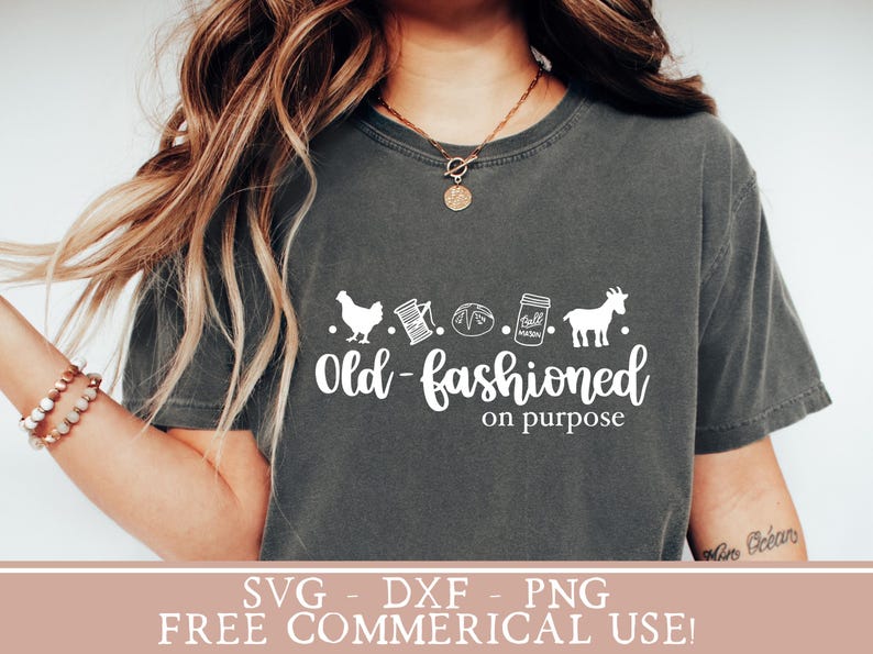 May include: A gray t-shirt with a white graphic design that says "Old-fashioned on purpose". The graphic includes a chicken, spool of thread, a loaf of bread, a jar of jam, and a goat.