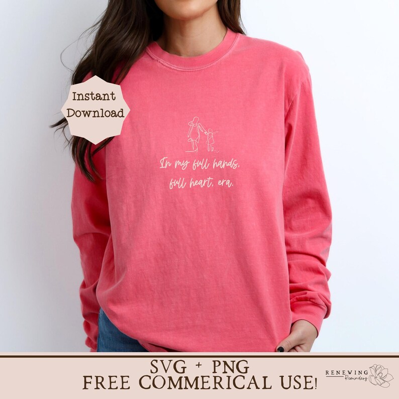 K&ouml;nnte beinhalten: Ein pinkfarbenes Langarmshirt mit einer wei&szlig;en Umrandung einer Mutter und eines Kindes, die gehen, und dem Text "In my full hands, full heart, era."