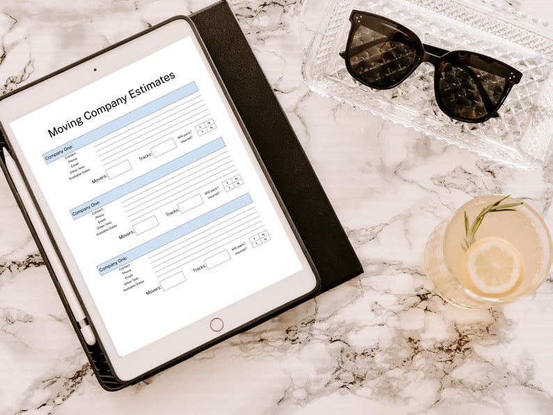 May include: A white tablet with a moving company estimates checklist. The checklist includes sections for company name, contact information, trucks, movers, and additional notes. The tablet is on a white marble surface with a glass of lemonade and sunglasses.