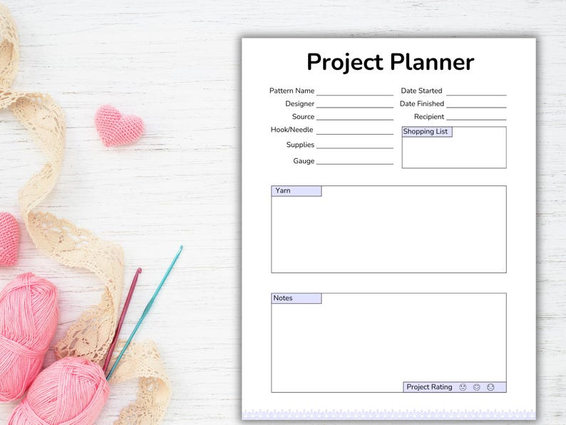 May include: A white Project Planner sheet with the title "Project Planner" at the top. The sheet has sections for pattern details, dates, and notes. Pink yarn balls, crochet hooks, and a pink heart are on the left.