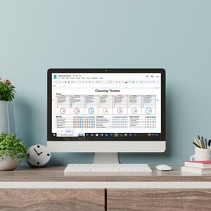 May include: A computer screen displaying a cleaning tracker spreadsheet with different colored sections for daily, weekly, monthly, quarterly, and once-a-year tasks. The spreadsheet is titled "Cleaning Tracker".
