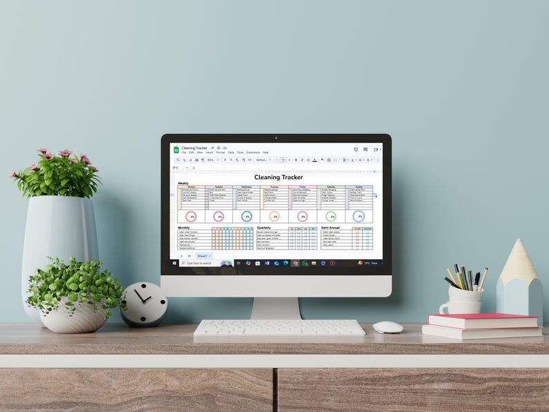 May include: A computer screen displaying a cleaning tracker spreadsheet with different colored sections for daily, weekly, monthly, quarterly, and once-a-year tasks. The spreadsheet is titled "Cleaning Tracker".