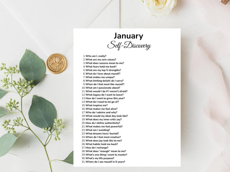 May include: A white sheet of paper with the title "January Self-Discovery" and a list of 31 questions for self-reflection. The paper is surrounded by decorative elements, including a gold wax seal and greenery.