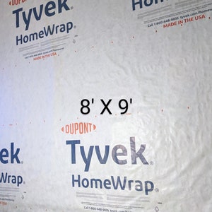 May include: A white Tyvek HomeWrap building wrap with the text "DUPONT Tyvek HomeWrap" and "Call 1-800-448-9835 tyvek.com/homewrap MADE IN THE USA" printed on it. The wrap is 8 feet by 9 feet.