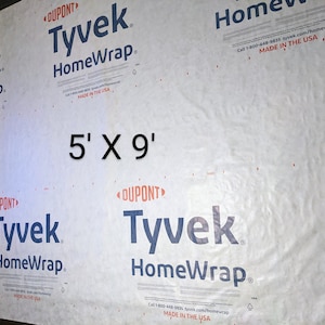 Könnte beinhalten: Eine weiße Tyvek HomeWrap-Bauplane mit dem aufgedruckten Text "5' X 9'". Die Plane wird von DuPont hergestellt und ist in den USA hergestellt.