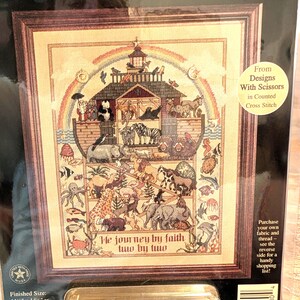 May include: A cross-stitch kit titled "Noah's Journey" featuring a framed design of Noah's Ark with animals, a rainbow, and the text "We journey by faith two by two." Finished size is 11.5" x 14.5".