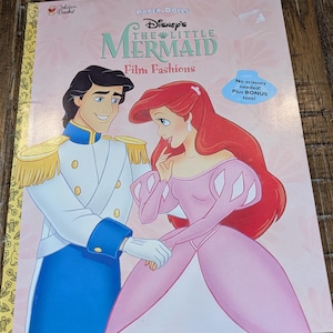 May include: A children's book titled "Disney's The Little Mermaid Film Fashions" featuring Ariel and Prince Eric. The cover is pink with illustrations of the characters and text. Includes a bonus tote. The Golden Books logo is in the upper left corner.