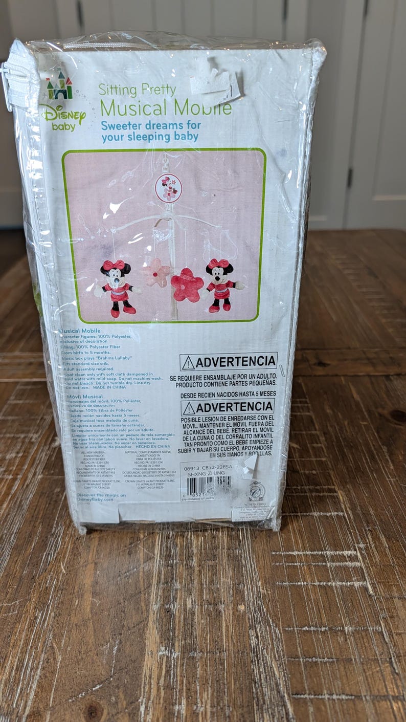 May include: A Disney baby musical mobile in a clear plastic package. The box features the text "Sitting Pretty Musical Mobile" and "Sweeter dreams for your sleeping baby." The mobile has Minnie Mouse and flower figures.