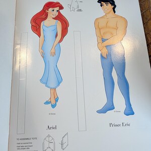 May include: Ariel and Prince Eric paper dolls from Disney's The Little Mermaid. Ariel is in a light blue dress with red hair. Prince Eric is shirtless with blue pants. The image includes instructions for assembling a tote.