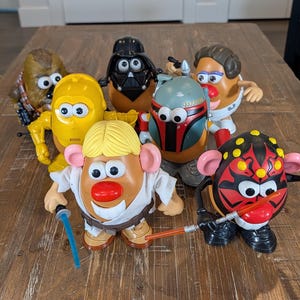 May include: A collection of Mr. Potato Head toys styled as Star Wars characters. The toys include Chewbacca, C-3PO, Darth Vader, Boba Fett, Luke Skywalker, and Darth Maul. Each toy has character-specific details and accessories, such as lightsabers.