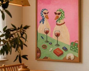 Op de afbeelding: Een ingelijst schilderij toont twee antropomorfe eenden met zonnebrillen en hoofddoeken, genietend van wijn en spelletjes. Het kunstwerk heeft een roze achtergrond en een groene tafel met dobbelstenen en een doos met het opschrift "JASTY".
