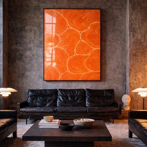 May include: A large rectangular wall art piece featuring vibrant orange swirling patterns in a black frame, positioned above a black leather sofa, a dark square coffee table with bowls, and two white mushroom-shaped lamps in a room.