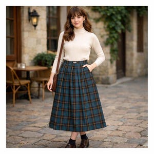 May include: A teal and navy plaid skirt with a pleated design. The skirt has a high waist and falls to mid-calf. The model is wearing a cream-colored turtleneck sweater and brown leather shoes. A brown leather purse is over the shoulder.