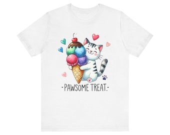 Könnte beinhalten: Weißes T-Shirt mit einer Aquarellillustration einer lächelnden Katze, die eine bunte Eistüte umarmt. Das Eis hat Kugeln aus grünem, blauem, rosa und lila Eis, garniert mit einer Kirsche. Der Text "-PAWSOME TREAT-" steht unter der Katze.