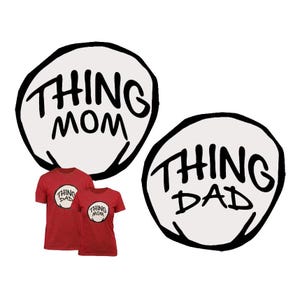 May include: Two red short-sleeved t-shirts featuring circular white patches with black hand-drawn style outlines. One shirt displays the text THING DAD in black, while the other displays the text THING MOM in black, both centered on the chest area.