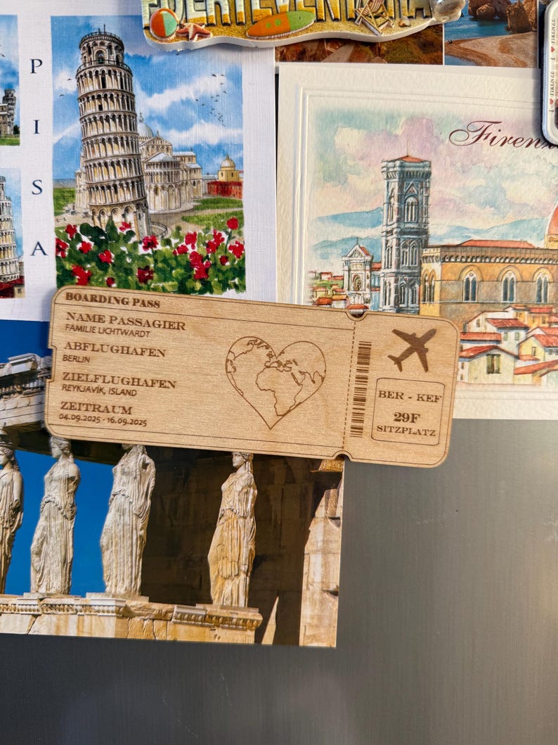 May include: A wooden boarding pass souvenir with a heart-shaped world map, airplane icon, and the text "BOARDING PASS", "NAME PASSAGIER", "FAMILIE LICHTWARDT", "ABFLUGHAFEN BERLIN", "ZIELFLUGHAFEN REYKJAVIK, ISLAND", "ZEITRAUM 04.09.2025-16.09.2025", "BER - KEF", "29F", and "SITZPLATZ".