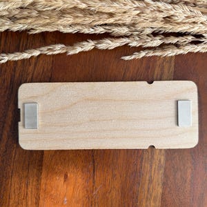 May include: A rectangular wooden sign with a natural wood finish. The sign has two silver metal magnets on the back.
