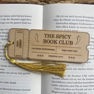 May include: A wooden bookmark with a chili pepper design and the text "The Spicy Book Club". The bookmark also includes the text "Location: Everywhere", "Time: Open End", and "Members Only".