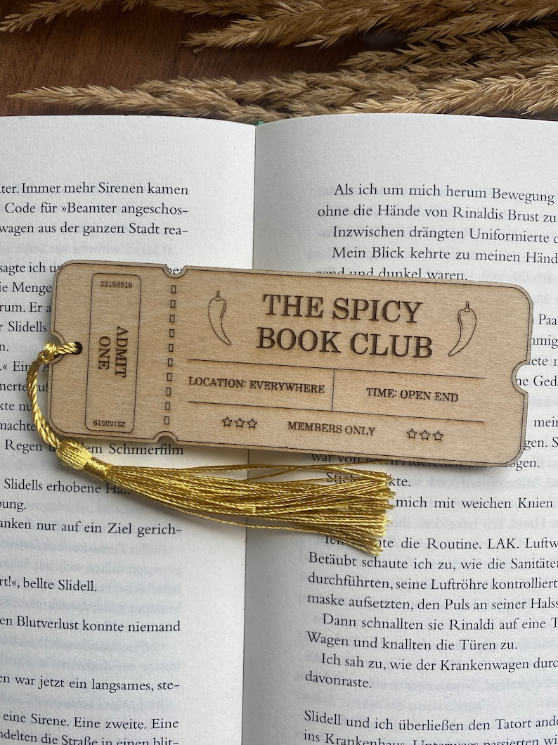May include: A wooden bookmark with a chili pepper design and the text "The Spicy Book Club". The bookmark also includes the text "Location: Everywhere", "Time: Open End", and "Members Only".