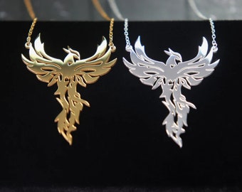 May include: Two phoenix necklaces, one gold and one silver, with intricate cutouts of the mythical bird. The necklaces are displayed on a black background.