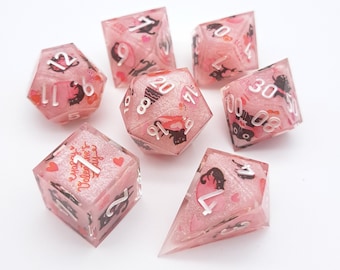 Op de afbeelding: Set roze glitter dobbelstenen met zwarte kattenillustraties en witte cijfers. De dobbelstenen zijn in de vorm van een kubus, een piramide en een ruit. De dobbelstenen hebben zinnen zoals "Happy Valentine's Day" en "Love is Love" erop gedrukt.