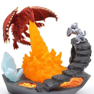 Puede incluir: Una figura de fantasía que representa un dragón rojo que exhala llamas naranjas hacia un caballero plateado. La base incluye un cristal azul y una caverna llena de lava, con el texto "Dragon of volcano caverns".