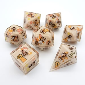 Op de afbeelding: Een set van zeven polyhedrale dobbelstenen met een beige achtergrond en heldere hars. Elke dobbelsteen heeft een corgi-hondontwerp met oranje, witte en bruine accenten. De cijfers zijn donkerbruin.