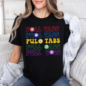 May include: Black t-shirt with a rainbow design that says "PULL TABS" with a different colored billiard ball in each word.