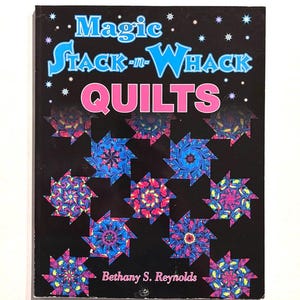 May include: A softcover book titled Magic Stack-n-Whack Quilts by Bethany S. Reynolds. The black cover features a repeating pattern of colorful, kaleidoscopic star-shaped quilt blocks in shades of blue, pink, and purple, accented by small white stars.