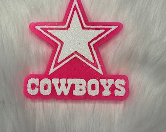 May include: Pink and white glitter star with the word "COWBOYS" underneath.
