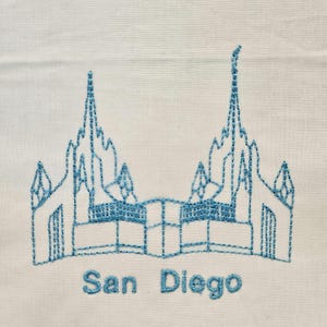May include: Embroidered design of a church building with the text "San Diego" underneath. The design is in blue thread on a white background.
