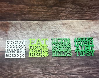 May include: Four St. Patrick's Day themed wooden signs with text in green and white. The signs read "Green Beers & Irish Cheers", "Eat Drink and Be Irish", "Lucky Charms & Chilled Beers", and "A Wee Bit Irish At Tipsy".