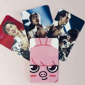 Könnte beinhalten: Eine Sammlung von K-Pop-Idol-Fotokarten mit mehreren Bildern desselben Künstlers in verschiedenen Posen, zusammen mit einer rosa Karte mit einem Cartoon-Schweinegesicht.