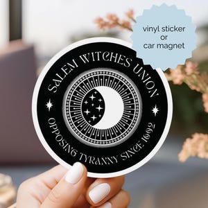 May include: A circular black and white sticker or car magnet featuring a crescent moon and star design at the center. The text reads SALEM WITCHES UNION and OPPOSING TYRANNY SINCE 1692. A light blue starburst shape contains the text vinyl sticker or car magnet.